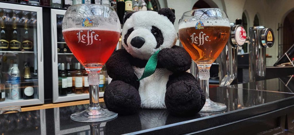 Panda with two glasses of Leffe Beer one on each side of him.